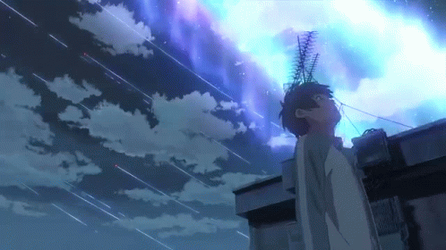 A Man Is Standing On Top Of A Building Looking Up At A Starry Night Sky . GIF