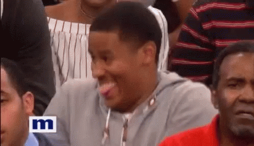 A Man Is Sticking Out His Tongue While Sitting In A Crowd . GIF
