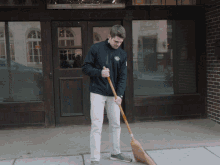A Man Is Sweeping The Sidewalk In Front Of A Brick Building GIF