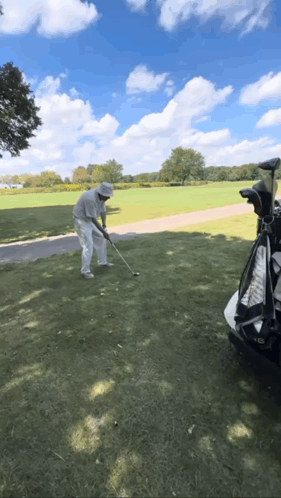A Man Is Swinging A Golf Club At A Golf Ball GIF
