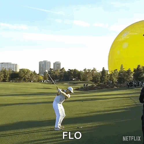 A Man Is Swinging A Golf Club On A Golf Course And The Word Flo Is Visible GIF