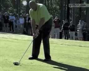 a man is swinging a golf club on a golf course while a crowd watches ..