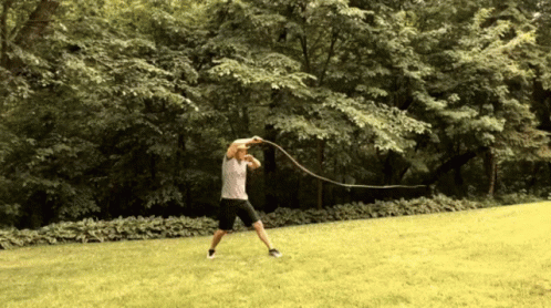A Man Is Swinging A Rope In A Park GIF