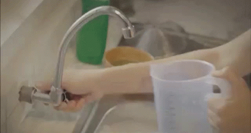 A Man Is Taking A Bath In A Bathtub And Holding A Bucket Of Water . GIF