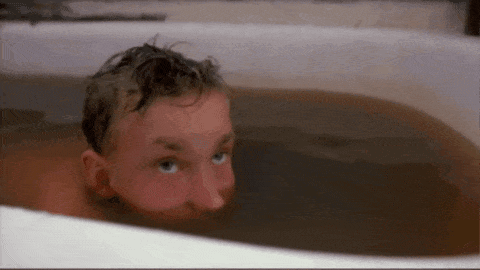 A Man Is Taking A Bath In A Bathtub With His Head Sticking Out Of It . GIF