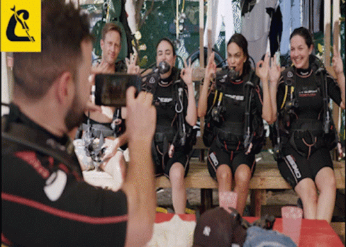A Man Is Taking A Picture Of A Group Of Scuba Divers Wearing Cressi Wet Suits GIF
