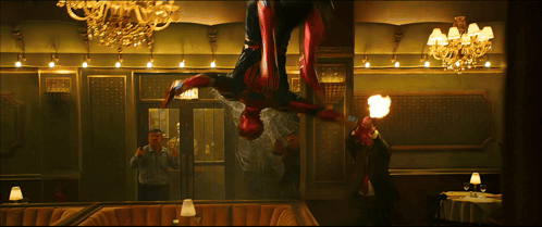A Man Is Taking A Picture Of A Man In A Spiderman Costume In A Restaurant GIF