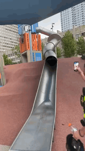 A Man Is Taking A Picture Of A Slide At A Playground GIF