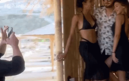 A Man Is Taking A Picture Of A Woman In A Bikini With The Hashtag #Lohan Beach Club GIF