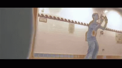 A Man Is Taking A Picture Of Himself In A Mirror . GIF