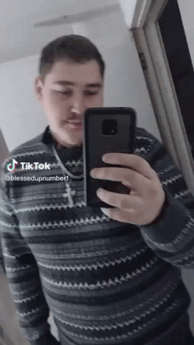 a man is taking a picture of himself in a mirror with a cross necklace on his neck
