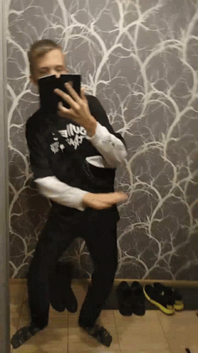 A Man Is Taking A Picture Of Himself In Front Of A Wall With A Pattern GIF
