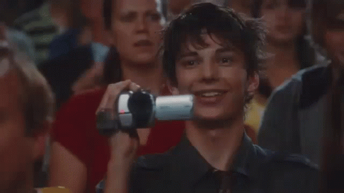A Man Is Taking A Picture Of Himself With A Camera In A Crowd . GIF
