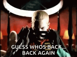 A Man Is Taking A Picture Of Himself With A Cell Phone And The Words `` Guess Who 'S Back ... Back Again '' . GIF