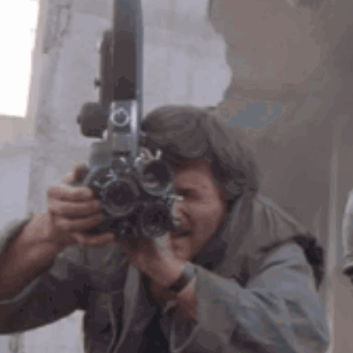 A Man Is Taking A Picture With A Camera In His Hands . GIF