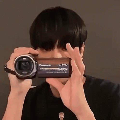A Man Is Taking A Picture With A Video Camera . GIF