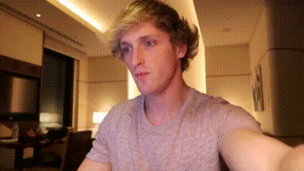 A Man Is Taking A Selfie In A Living Room While Wearing A Gray Shirt . GIF