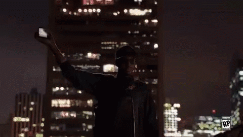 A Man Is Taking A Selfie In Front Of A Large Screen With The Letters Rp On It GIF