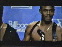 A Man Is Talking Into A Microphone In Front Of A Wall That Says Billboard GIF