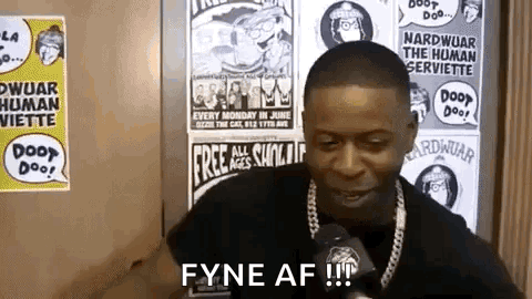 a man is talking into a microphone in front of a wall with posters .