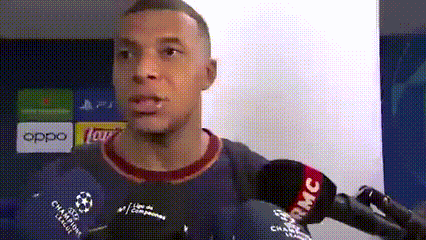 A Man Is Talking Into A Microphone While Wearing A Blue Shirt With A Soccer Ball On It . GIF