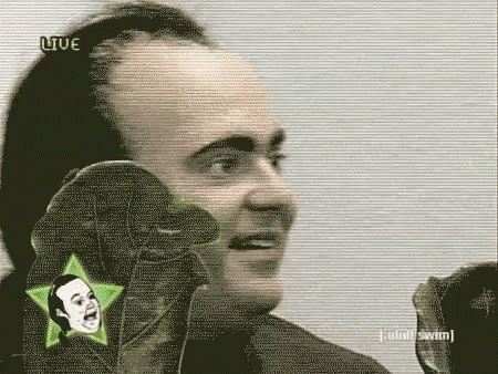 A Man Is Talking Into A Microphone While Wearing A Pair Of Gloves With A Star On It . GIF