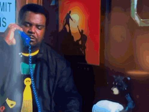 A Man Is Talking On A Blue Phone In Front Of A Sign That Says Mit GIF