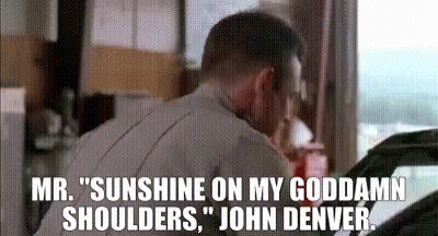 A Man Is Talking On A Cell Phone In A Garage While Looking At A Car . GIF