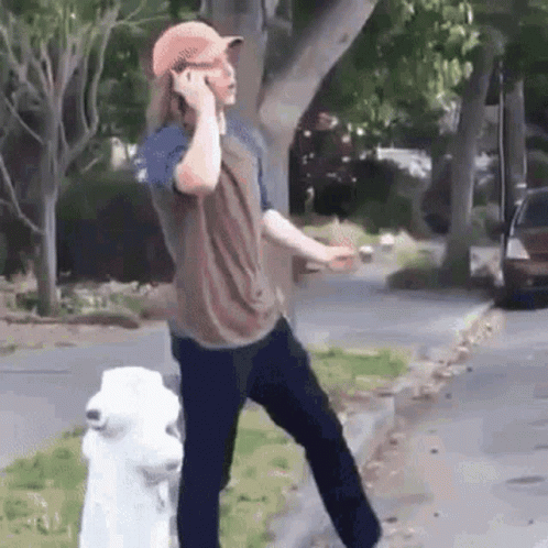 A Man Is Talking On A Cell Phone Next To A Fire Hydrant . GIF