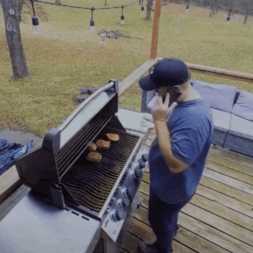 A Man Is Talking On A Cell Phone While Grilling GIF
