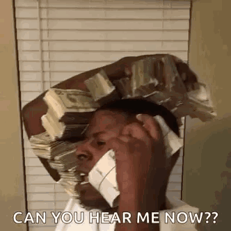 A Man Is Talking On A Cell Phone While Holding A Stack Of Money On His Head . GIF