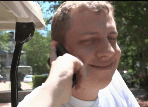 a man is talking on a cell phone while sitting in a golf cart