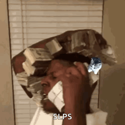 A Man Is Talking On A Cell Phone While Wearing A Hat Made Of Money . GIF