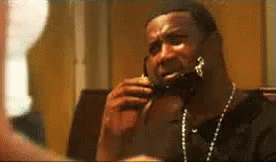 A Man Is Talking On A Cell Phone While Wearing A Necklace . GIF