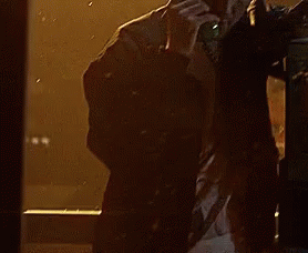 A Man Is Talking On A Phone In Front Of A Window With Rain Drops On It GIF