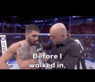 A Man Is Talking To Another Man In A Boxing Ring While A Referee Looks On . GIF