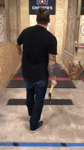 A Man Is Throwing An Axe At A Chopper 'S Sign GIF