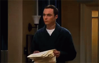 A Man Is Throwing Papers In The Air While Standing In A Hallway . GIF