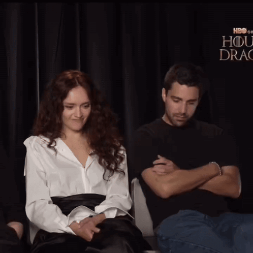 A Man Is Touching A Woman 'S Ear In Front Of A Sign That Says Hbo GIF