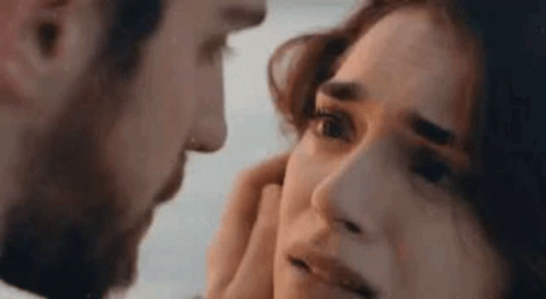A Man Is Touching A Woman 'S Face With His Hand . GIF