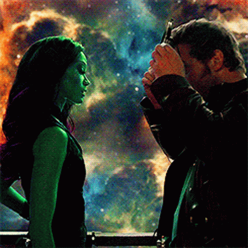A Man Is Touching A Woman 'S Forehead In Front Of A Galaxy . GIF
