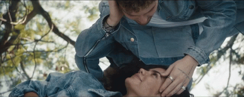 A Man Is Touching A Woman 'S Forehead While Laying Down GIF