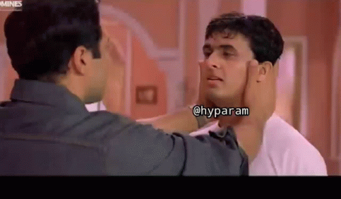 A Man Is Touching Another Man 'S Face In A Room . GIF