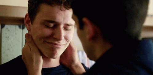 A Man Is Touching Another Man 'S Face While They Are Standing Next To Each Other . GIF