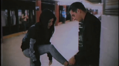 A Man Is Tying A Woman 'S Shoe In A Subway Station GIF