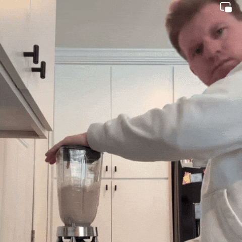 A Man Is Using A Blender In A Kitchen With A T On The Cabinet GIF
