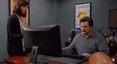 A Man Is Using A Computer While A Woman Looks On GIF