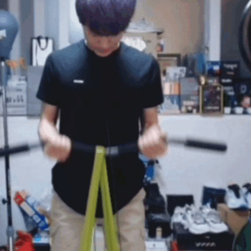 A Man Is Using A Green Resistance Band To Exercise . GIF