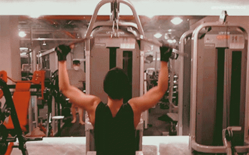 A Man Is Using A Machine In A Gym That Says Lat Pull Down GIF