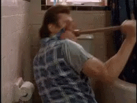 A Man Is Using A Plunger To Clean A Toilet . GIF
